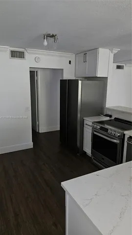 a kitchen with granite countertop a refrigerator and a stove top oven