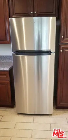 a view of a refrigerator in kitchen and empty room