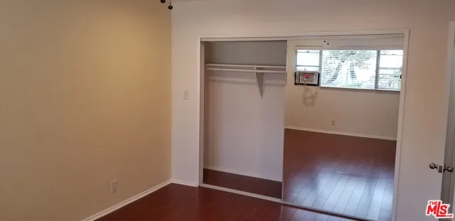 an empty room with wooden floor cabinet and windows