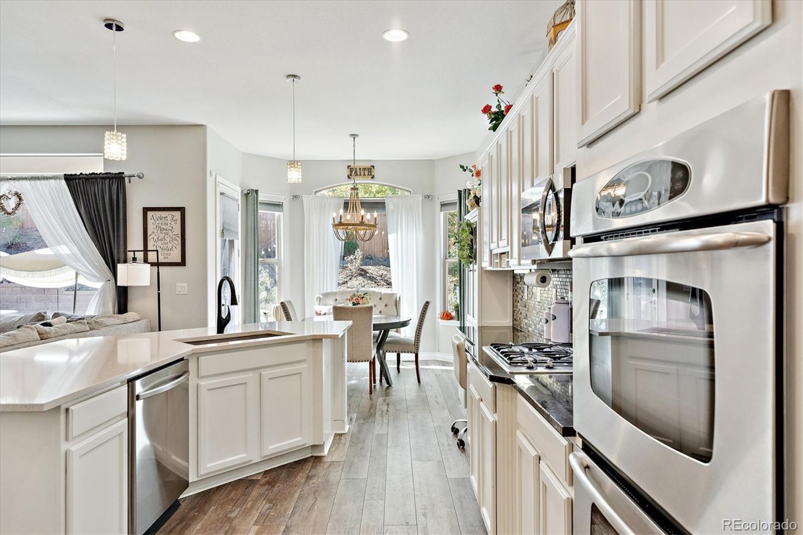 11641 Colony Loop Parker, CO 80138 - Photo 15 of 37 a kitchen with white cabinets and stainless steel appliances