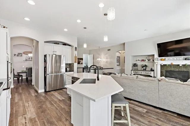 a kitchen with stainless steel appliances kitchen island granite countertop a refrigerator a stove a microwave oven a sink with island and chairs