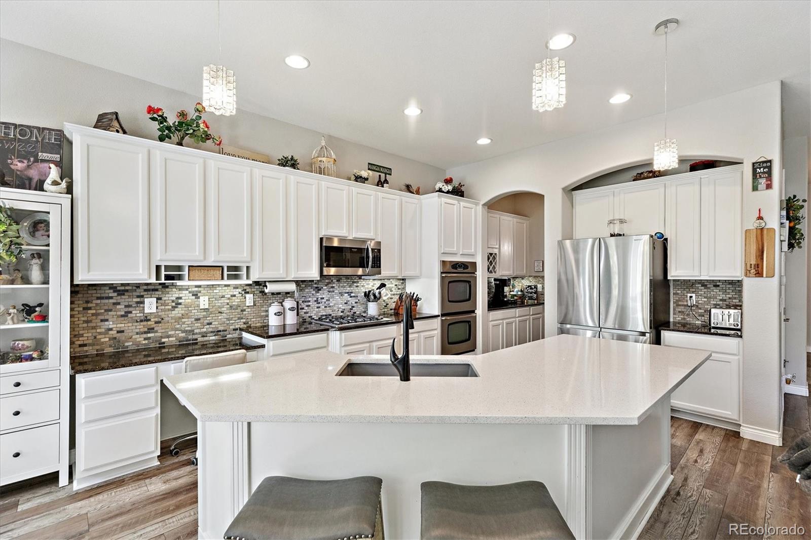11641 Colony Loop Parker, CO 80138 - Photo 17 of 37 a kitchen with stainless steel appliances kitchen island granite countertop a kitchen island and chairs in it