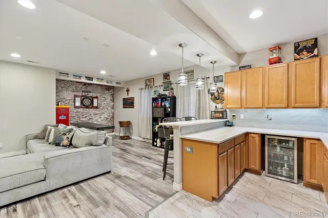 a living room with kitchen island a stove a sink and a refrigerator
