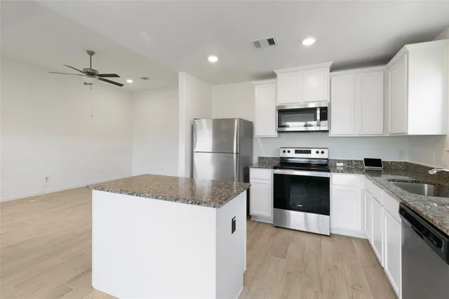 a kitchen with granite countertop a refrigerator and a stove top oven