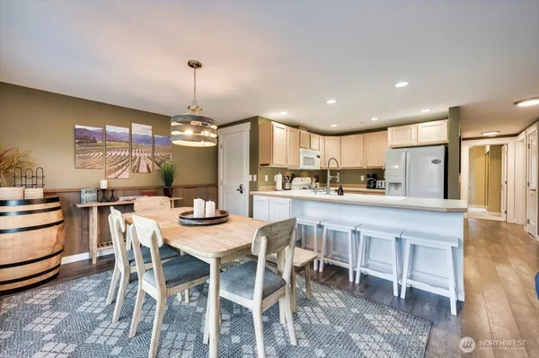 a kitchen with stainless steel appliances kitchen island granite countertop a dining table chairs and white cabinets