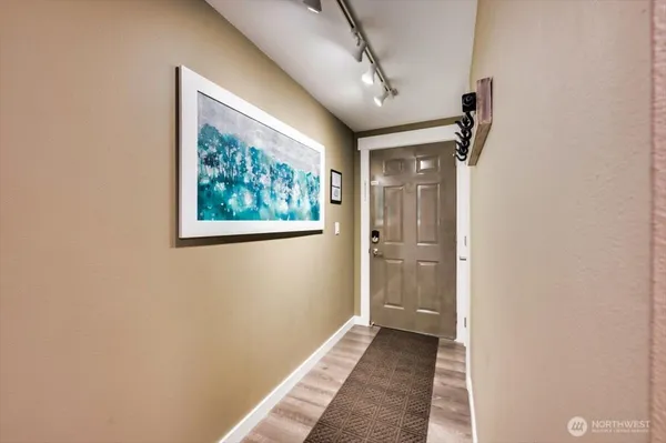 a view of a hallway with wooden floor and a bathroom