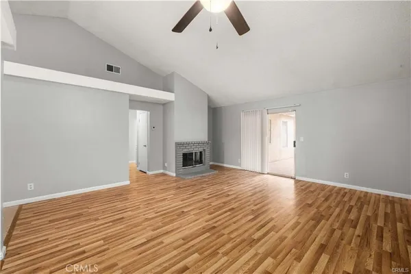 a view of empty room with wooden floor and ceiling fan