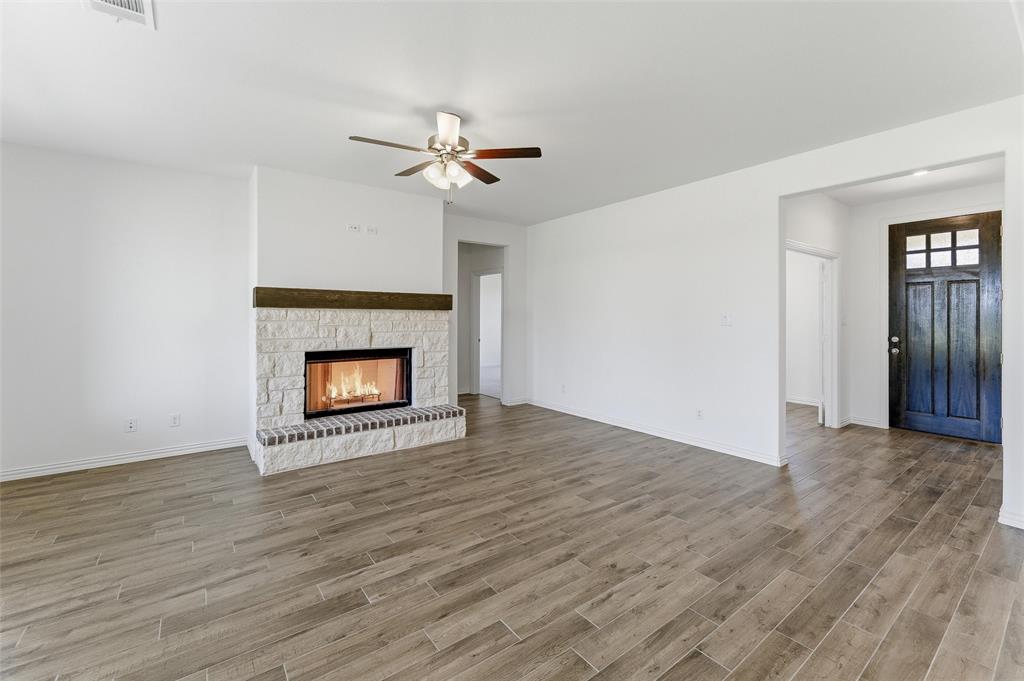 130 Fossil Canyon Drive Rhome, TX 76078 - Photo 10 of 25 Living area featuring a stone-clad fireplace with a wood mantel