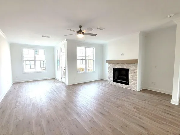an empty room with wooden floor fireplace and windows
