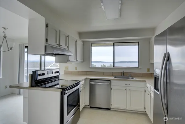 a kitchen with white cabinets stainless steel appliances and a window