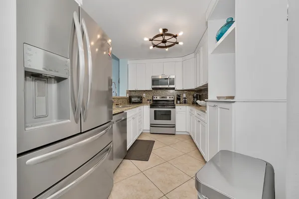 a kitchen with granite countertop white cabinets and stainless steel appliances