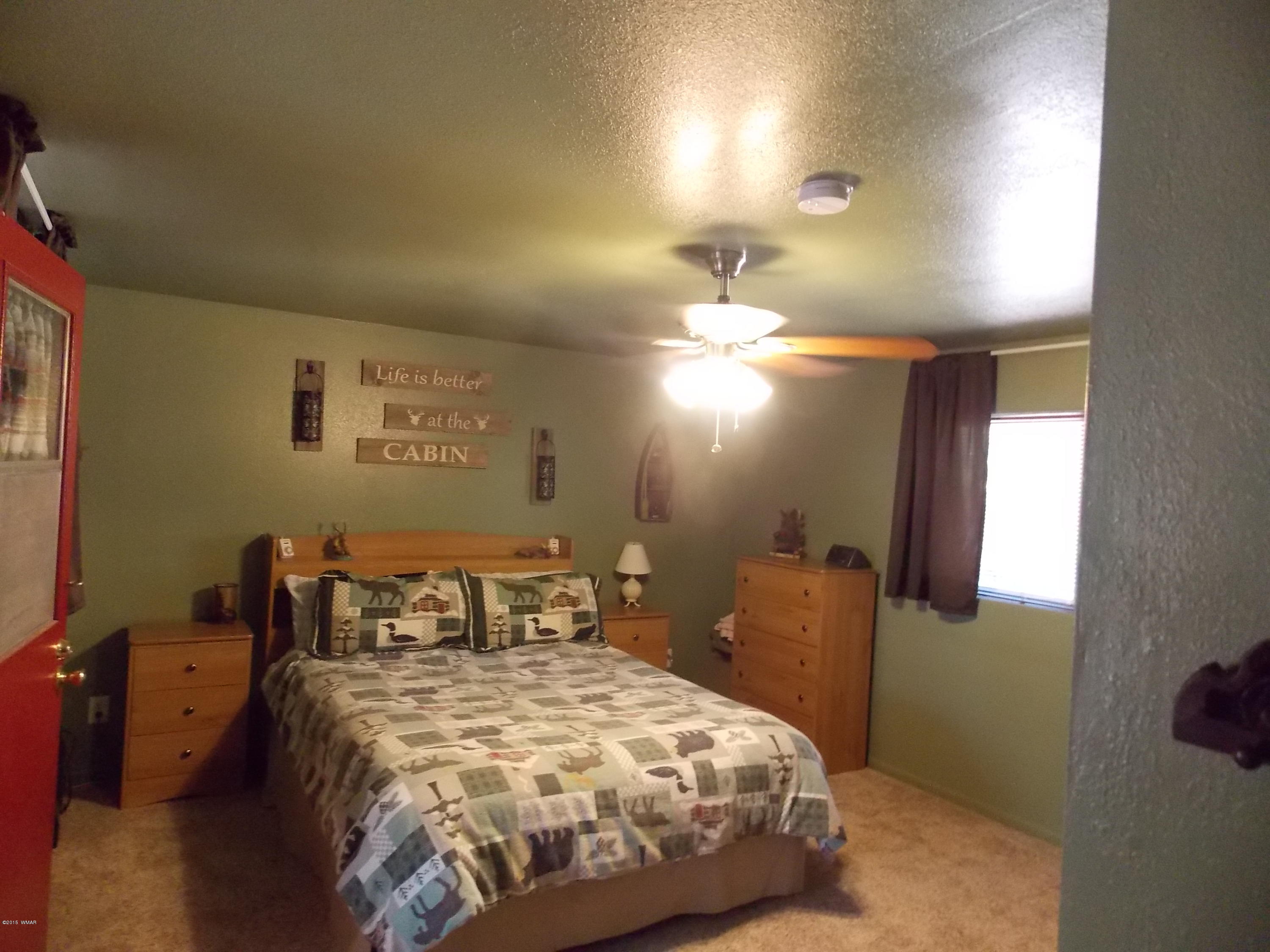 2886 Big Pine Road Overgaard, AZ 85933 - Photo 8 of 25 a bedroom with a bed and a lamp with window