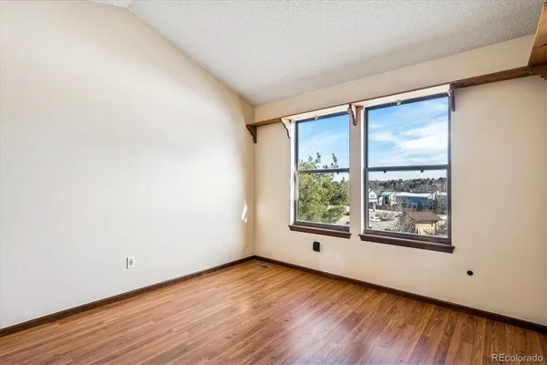 a view of an empty room with window and wooden floor