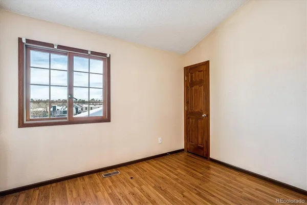 an empty room with wooden floor and windows
