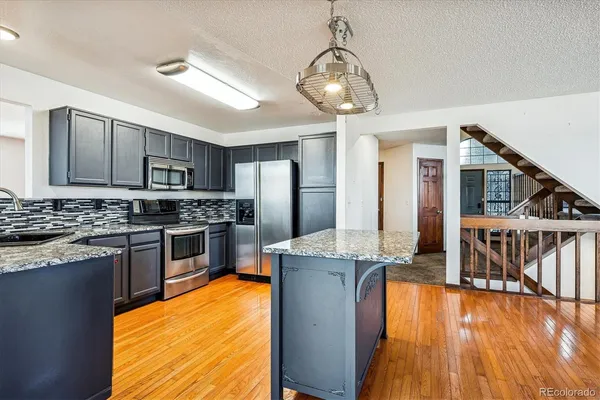 a kitchen with kitchen island granite countertop a sink cabinets and stainless steel appliances