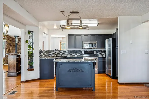 a kitchen with granite countertop wooden cabinets stainless steel appliances and a wooden floor