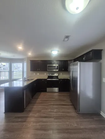 a large kitchen with stainless steel appliances granite countertop a refrigerator and a stove