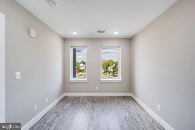an empty room with wooden floor and window
