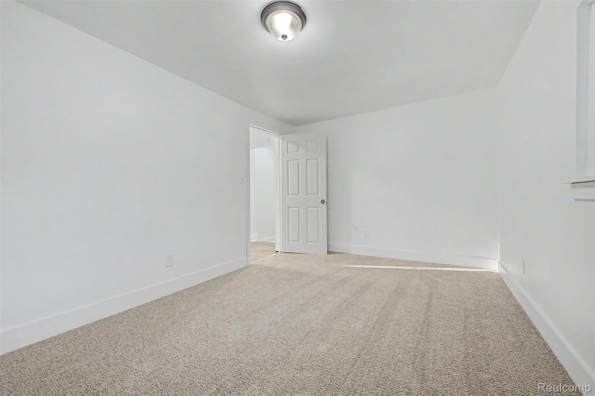 26718 Penn Street Inkster, MI 48141 - Photo 21 of 27 Carpeted room with white walls, white baseboards, a white paneled door, and a flush mount ceiling light fixture