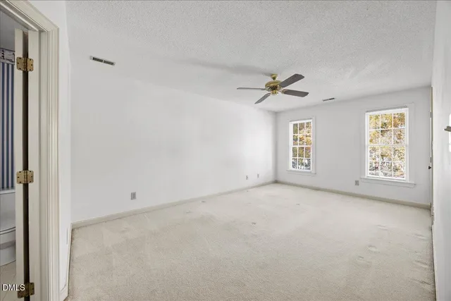 an empty room with windows and ceiling fan