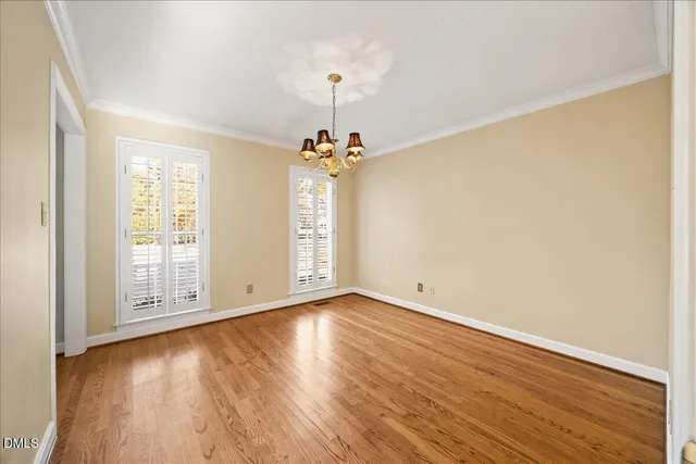 an empty room with wooden floor chandelier fan and windows