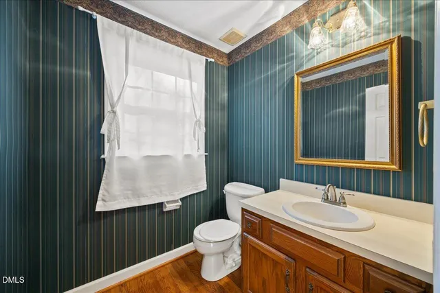 a bathroom with a granite countertop sink toilet a mirror and a window