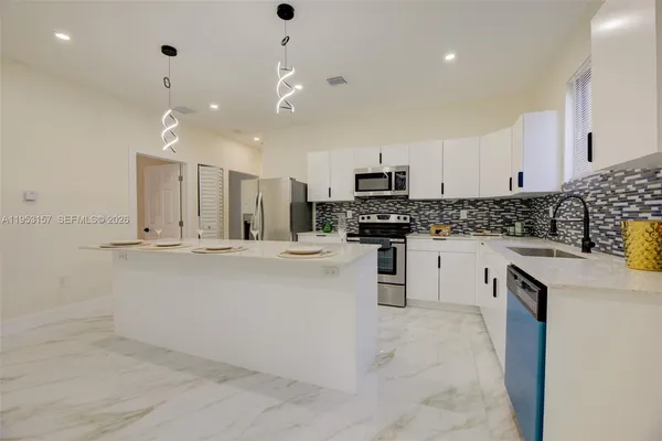 a kitchen with kitchen island white cabinets and stainless steel appliances