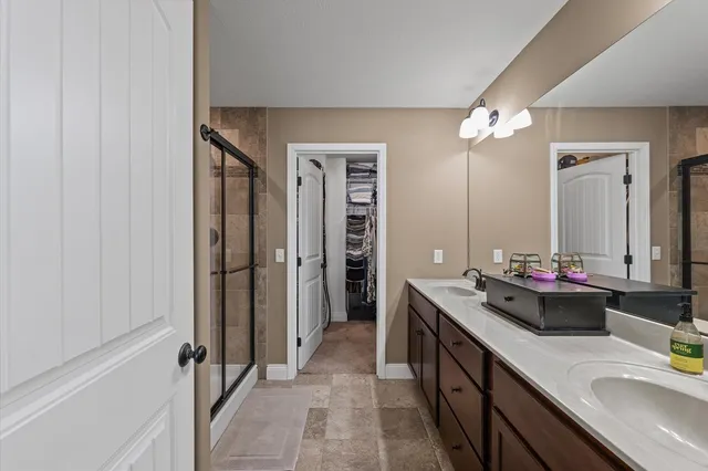 a bathroom with a double vanity sink a mirror and a shower