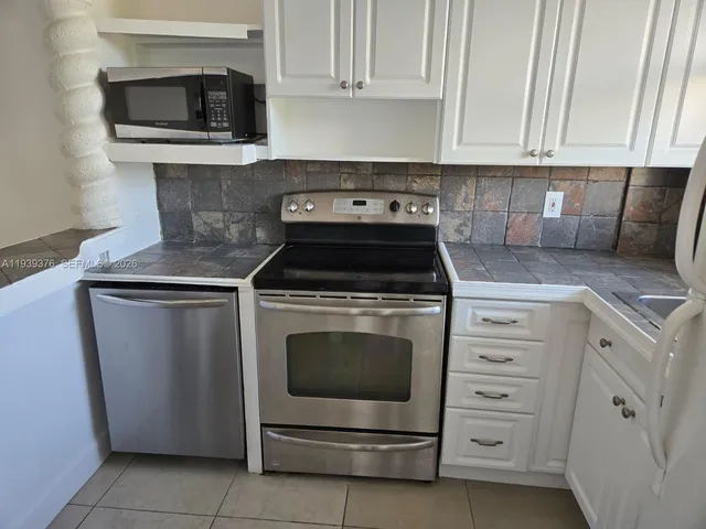 a kitchen with granite countertop white cabinets and stainless steel appliances