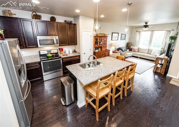 a kitchen with stainless steel appliances granite countertop a refrigerator a stove a sink a microwave and island
