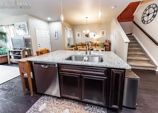 a view of kitchen island with granite countertop a stove a sink a dining table and chairs