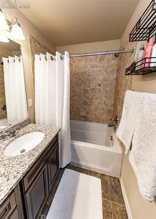 a bathroom with a granite countertop sink and a bathtub