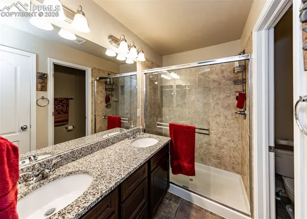 a bathroom with a granite countertop sink a mirror and shower