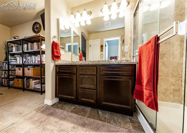 a bathroom with a granite countertop shower a sink and a mirror