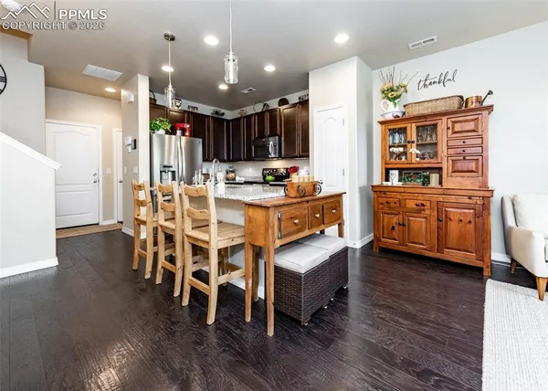 a kitchen with stainless steel appliances kitchen island granite countertop a table chairs and a refrigerator