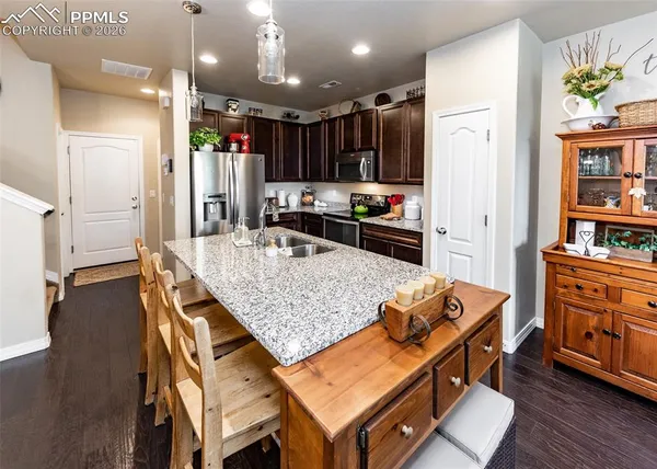 a kitchen with stainless steel appliances granite countertop a stove refrigerator and wooden floor