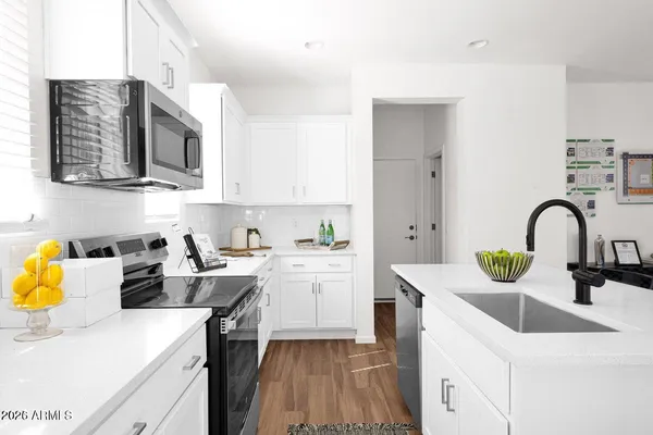 a kitchen with stainless steel appliances a sink a stove a microwave a refrigerator and cabinets