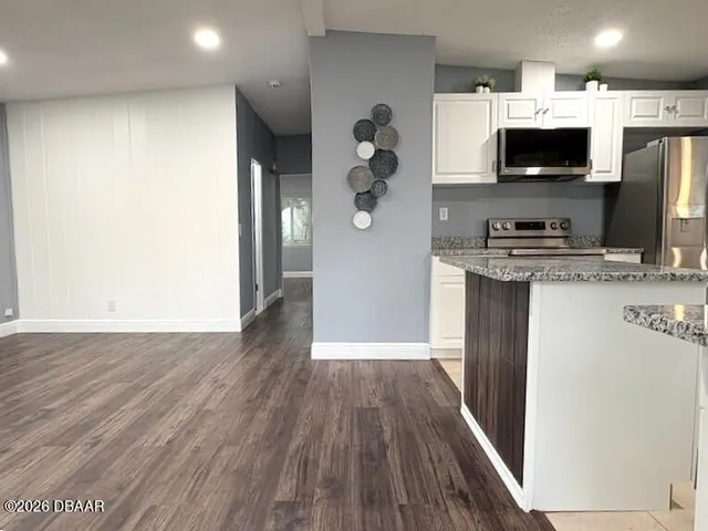 a view of kitchen with stainless steel appliances kitchen island wooden floor and window