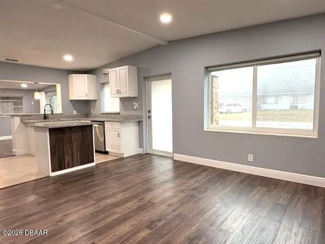 a view of kitchen with kitchen island wooden floors and stainless steel appliances