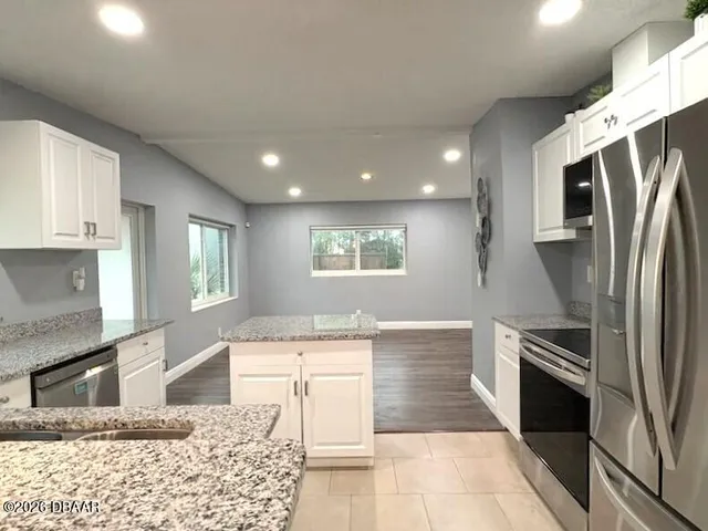 a large kitchen with stainless steel appliances kitchen island granite countertop a refrigerator and a sink