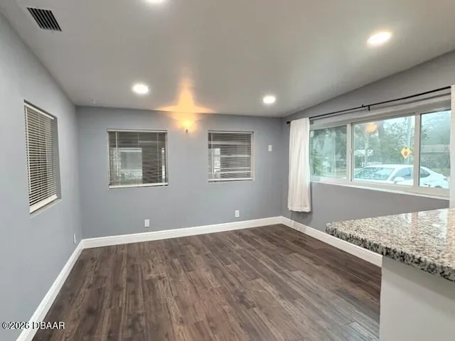 a view of an empty room with a window and wooden floor