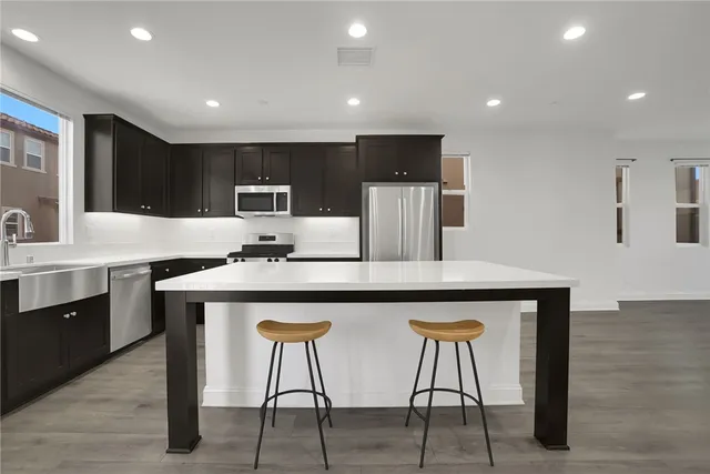 a kitchen with stainless steel appliances a kitchen island hardwood floor sink and stove