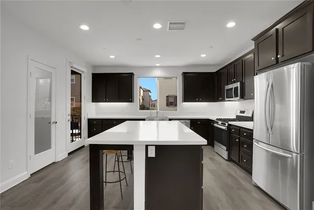 a large kitchen with stainless steel appliances kitchen island granite countertop a refrigerator a sink a stove and a wooden cabinets