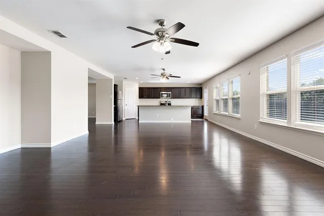 a view of empty room with wooden floor and ceiling fan