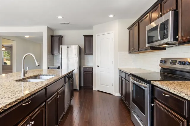 a kitchen with stainless steel appliances granite countertop a stove top oven a sink and dishwasher