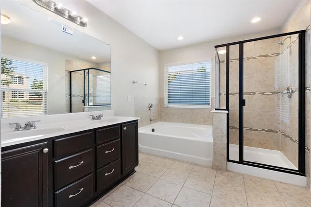 a spacious bathroom with a tub sink shower and mirror