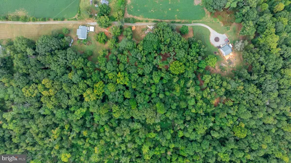 an aerial view of residential house with outdoor space and trees all around