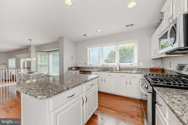 a kitchen with stainless steel appliances granite countertop a stove a sink and a microwave
