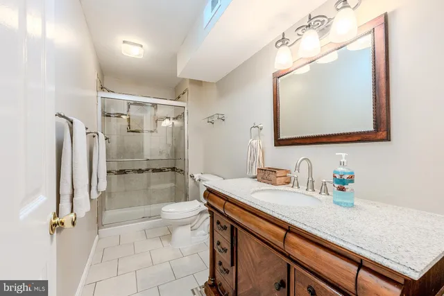 a bathroom with a sink a toilet a mirror and shower