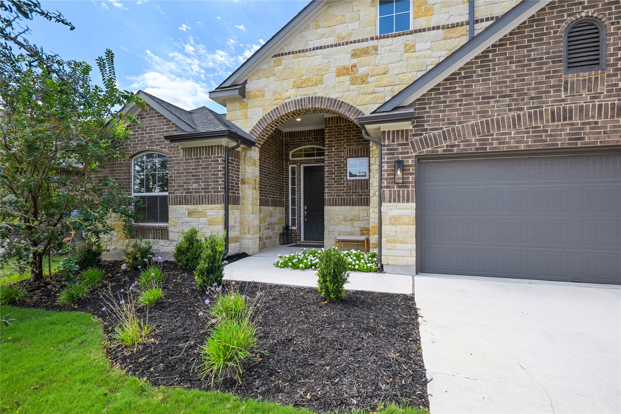 238 Wild Pecan Loop Buda, TX 78610 - Photo 29 of 31 Striking brick and stone masonry shapes the grand arched entry of this custom home.